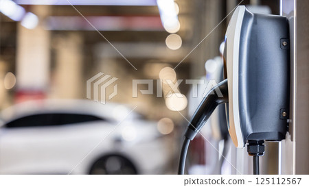 EV charging station and electric car, Electric car charging station for charge EV battery, Plug for vehicle with electric engine, EV charger clean energy, Charging point at car parking lot. 125112567