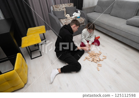 Creative bonding time in a cozy living room as a child practices building skills with wooden blocks in winter 125112598