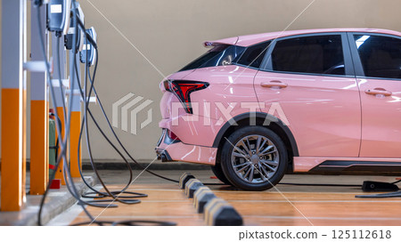 EV charging station and electric car, Electric car charging station for charge EV battery, Plug for vehicle with electric engine, EV charger clean energy, Charging point at car parking lot. 125112618