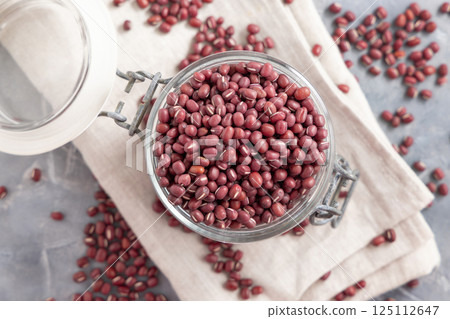 Glass jar full of azuki beans on gray top view. Dried uncooked legumes. Vegetarian protein 125112647