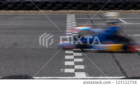 Motion blur kart driver crossing the start and finish line on kart race track circuit, Go kart racer crossing the start and finish line, Extreme sport competition winner. 125112738