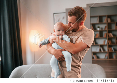 Holding kid in hands. Father with his newborn baby is indoors. Conception of single dad 125113213