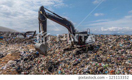 Bulldozer working on massive lanfill waste site with mountain background, Heavy machinery manage plastic waste at larg garbage dump, Excavtor at landfill global waste crisis concept. Bulldozer working on massive lanfill waste site with mountain background, Heavy machinery manage plastic waste at larg garbage dump, Excavtor at landfill global waste crisis concept. 125113352
