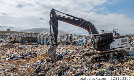 Bulldozer working on massive lanfill waste site with mountain background, Heavy machinery manage plastic waste at larg garbage dump, Excavtor at landfill global waste crisis concept. Bulldozer working on massive lanfill waste site with mountain background, Heavy machinery manage plastic waste at larg garbage dump, Excavtor at landfill global waste crisis concept. 125113365