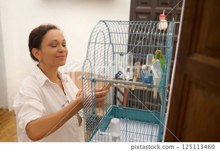 Woman Tending to Colorful Birds in a Scenic Indoor Setting 125113460