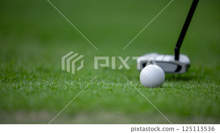 Putter and golf ball on green grass, Golf putter putting golf ball to the hole. 125113536