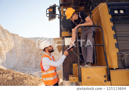 Taking the documents. Two men in uniform are working together in the quarry 125113604