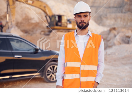 Posing for a camera. Man in uniform is working in the quarry at daytime 125113614