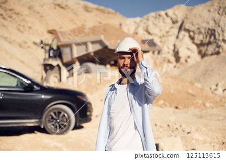 Posing for a camera. Man in uniform is working in the quarry at daytime Posing for a camera. Man in uniform is working in the quarry at daytime 125113615