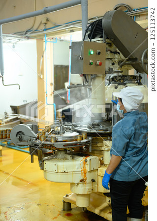 Factory employee wearing protective clothes managing canning process in factory 125113742