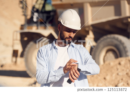 Checking time. Man in uniform is working in the quarry at daytime 125113872