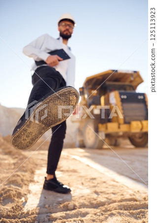 Having fun, making a kick by leg. Man in uniform is working in the quarry at daytime 125113923