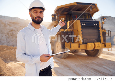 Smart person is with documents in hands. Man in uniform is working in the quarry at daytime 125113927
