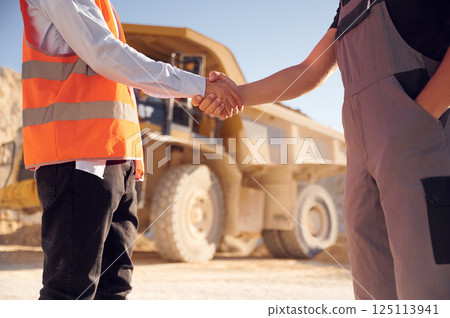 Making a deal. Doing handshake. Two men in uniform are working together in the quarry Making a deal. Doing handshake. Two men in uniform are working together in the quarry 125113941