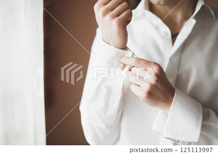 Grooms morning preparation. Handsome man getting dressed and preparing for the wedding Grooms morning preparation. Handsome man getting dressed and preparing for the wedding 125113997