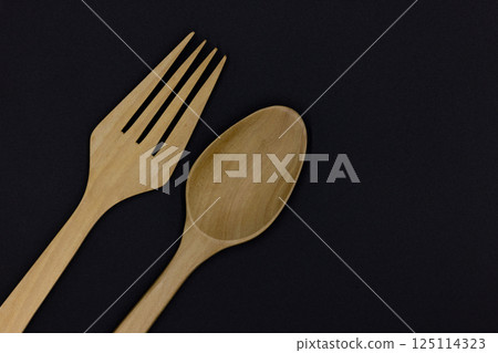 Wooden spoon and fork on black background, One set of wood spoon and fork kitchen ware, Eco friendly Wooden fork and spoon, Top view 125114323