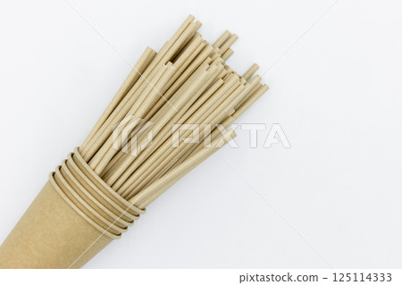 Paper cups and paper straws on white background, Accessories for drinking outdoors, Ecology recycling eco friendly, Eco friendly reusable paper straws, Kraft paper straw for drinking coffee or tea. 125114333