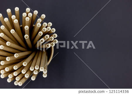 Paper straws on black background, Paper straws, Accessories for drinking outdoors, Ecology recycling eco friendly, Eco friendly reusable paper straws, Kraft paper straw for drinking coffee or tea. Paper straws on black background, Paper straws, Accessories for drinking outdoors, Ecology recycling eco friendly, Eco friendly reusable paper straws, Kraft paper straw for drinking coffee or tea. 125114336