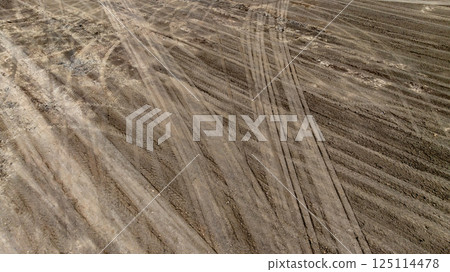 Tyre track on dirt sand or mud off road track, Tire mark ground vehicle wheel shape, Dirt soil texture, Top view tires tracks on dry mud background and texture. Tyre track on dirt sand or mud off road track, Tire mark ground vehicle wheel shape, Dirt soil texture, Top view tires tracks on dry mud background and texture. 125114478