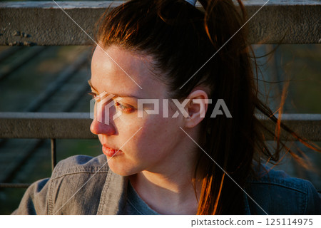 Pensive woman on bridge at sunset for reflective mood themes 125114975