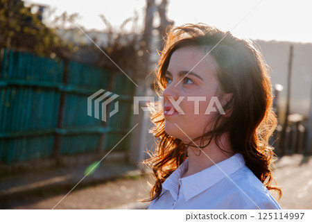 Woman enjoying sunset outdoors during golden hour 125114997