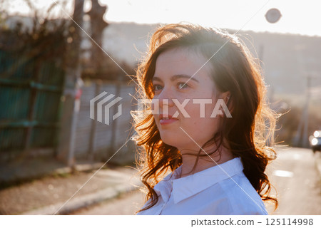 Woman with sunlit hair in outdoor urban setting Woman with sunlit hair in outdoor urban setting 125114998