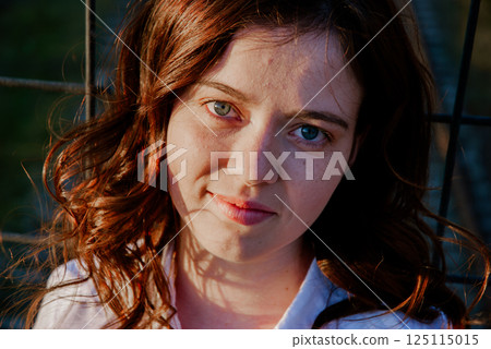 Portrait of a woman with red hair in sunlit outdoor setting 125115015