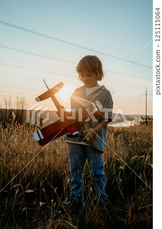 Smiling preschool child boy plays with craft wooden retro styled airplane Smiling preschool child boy plays with craft wooden retro styled airplane 125115064