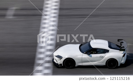 Motion blurred super car crossing finish line checkered on race track circuit, Race super car blurred motion crossing finish checkered line on race track, concept win and goal reached. 125115216