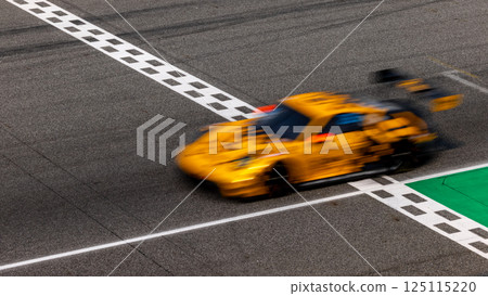 Motion blurred super car crossing finish line checkered on race track circuit, Race super car blurred motion crossing finish checkered line on race track, concept win and goal reached. Motion blurred super car crossing finish line checkered on race track circuit, Race super car blurred motion crossing finish checkered line on race track, concept win and goal reached. 125115220