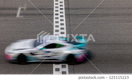 Motion blurred super car crossing finish line checkered on race track circuit, Race super car blurred motion crossing finish checkered line on race track, concept win and goal reached. Motion blurred super car crossing finish line checkered on race track circuit, Race super car blurred motion crossing finish checkered line on race track, concept win and goal reached. 125115223