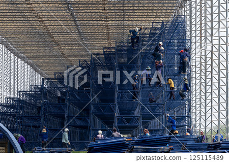 All workers to build scaffold for working at height of building under construction, Group man worker  working on assembly of scaffold, Worker installing scaffolding on building showcasing teamwork 125115489