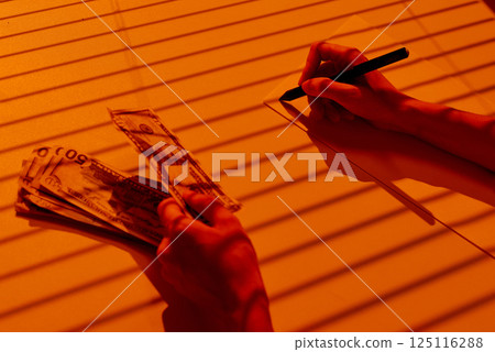 Writing Notes While Counting US Dollar Banknotes. 125116288