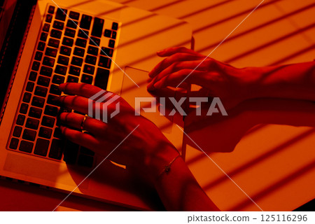 Woman Working on Laptop with Blinds Shadows in Warm Light. Woman Working on Laptop with Blinds Shadows in Warm Light. 125116296
