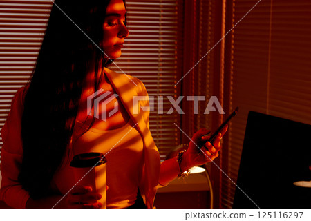 Business Woman Holding Coffee Cup and Phone in Sunset Light. Business Woman Holding Coffee Cup and Phone in Sunset Light. 125116297