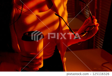 Closeup of Woman with Coffee and Glasses in Warm Office Light. 125116326
