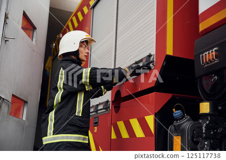 Taking equipment from the truck. Woman firefighter in uniform is at work in department 125117738