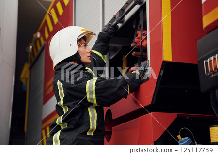Taking equipment from the truck. Woman firefighter in uniform is at work in department 125117739