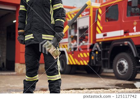In uniform with axe in hands. Woman firefighter is at work in department 125117742