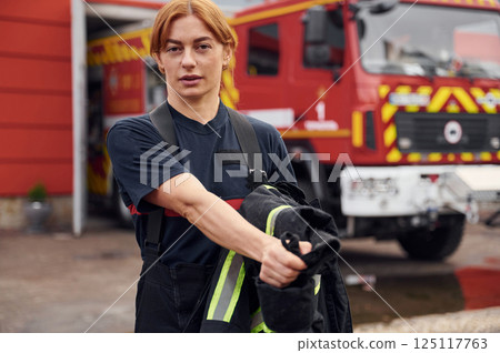 Taking off the protective clothes. Woman firefighter in uniform is at work in department Taking off the protective clothes. Woman firefighter in uniform is at work in department 125117763