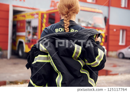 Taking off the protective clothes. Woman firefighter in uniform is at work in department Taking off the protective clothes. Woman firefighter in uniform is at work in department 125117764