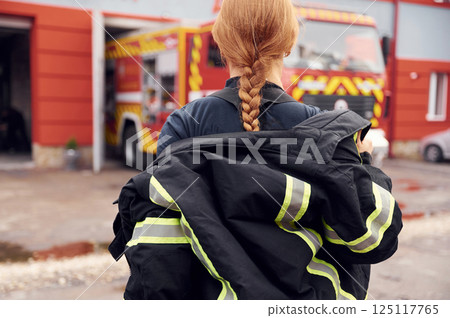 Taking off the protective clothes. Woman firefighter in uniform is at work in department Taking off the protective clothes. Woman firefighter in uniform is at work in department 125117765