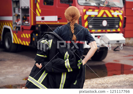 Rear view. Woman firefighter in uniform is at work in department 125117766
