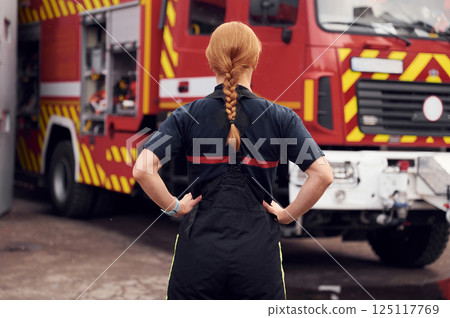 Rear view. Woman firefighter in uniform is at work in department Rear view. Woman firefighter in uniform is at work in department 125117769