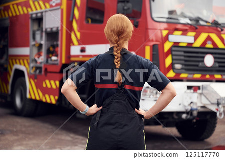 Rear view. Woman firefighter in uniform is at work in department Rear view. Woman firefighter in uniform is at work in department 125117770