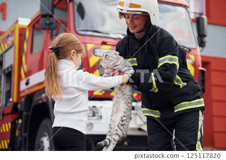 Near the truck. With scottish fold cat. Firefighter woman in uniform is with a little girl Near the truck. With scottish fold cat. Firefighter woman in uniform is with a little girl 125117820