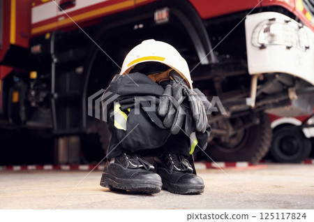 Close up view of firefighter's hat, gloves, jacket, pants and shoes. With big vehicle 125117824