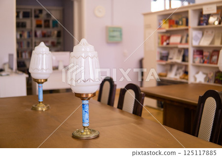 Vintage lamps on a table in a traditional public library with bookshelfs 125117885