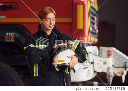 Holding helmet. Woman firefighter in uniform is at work in department Holding helmet. Woman firefighter in uniform is at work in department 125117889