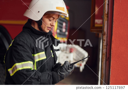 Using radio transmitter. Woman firefighter in uniform is at work in department Using radio transmitter. Woman firefighter in uniform is at work in department 125117897